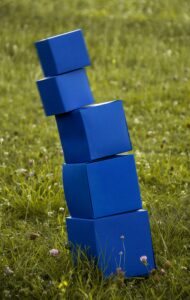 Blauwe blokkentoren valt bijna om in gras - mihaly-koles-oFN1FCOBE2I-unsplash